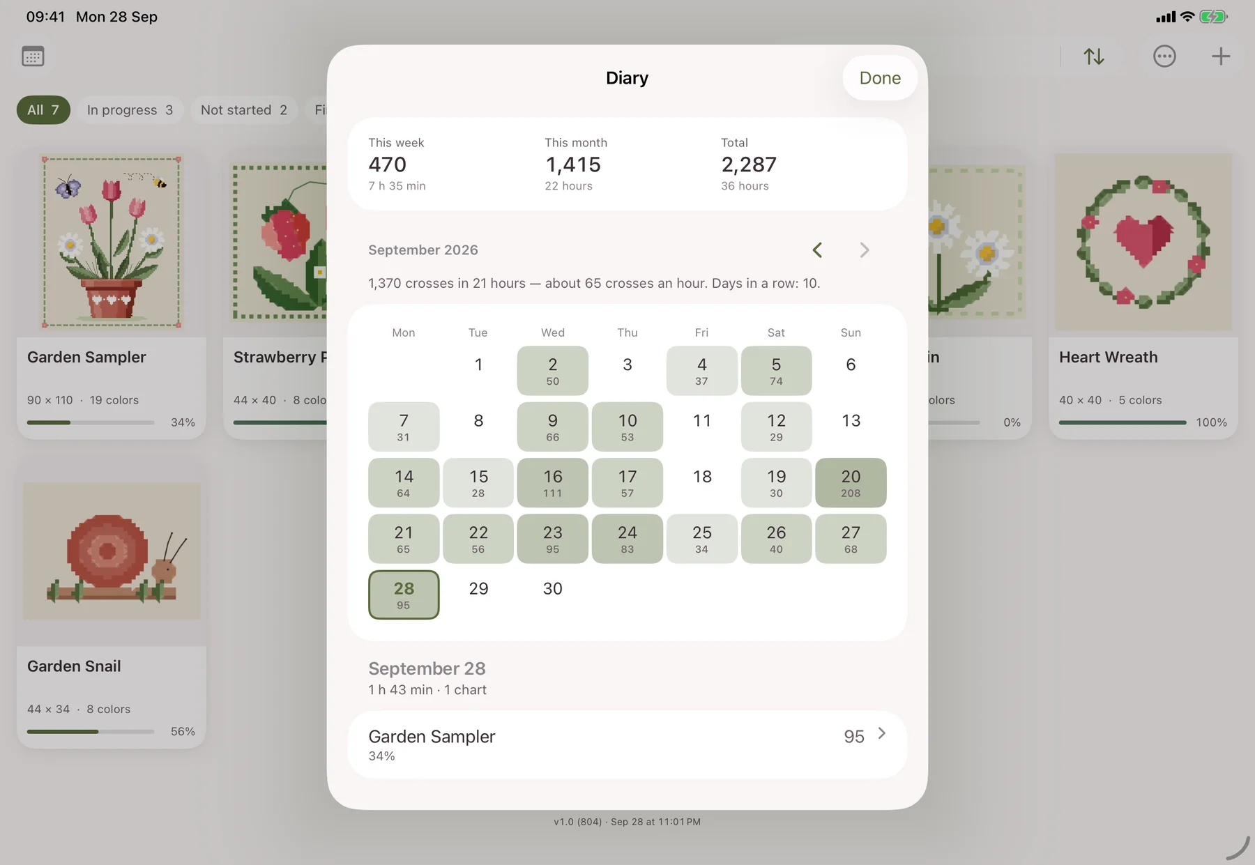 Stitch Garden on iPad: the stitching diary open as a card over a shelf of cross-stitch charts
